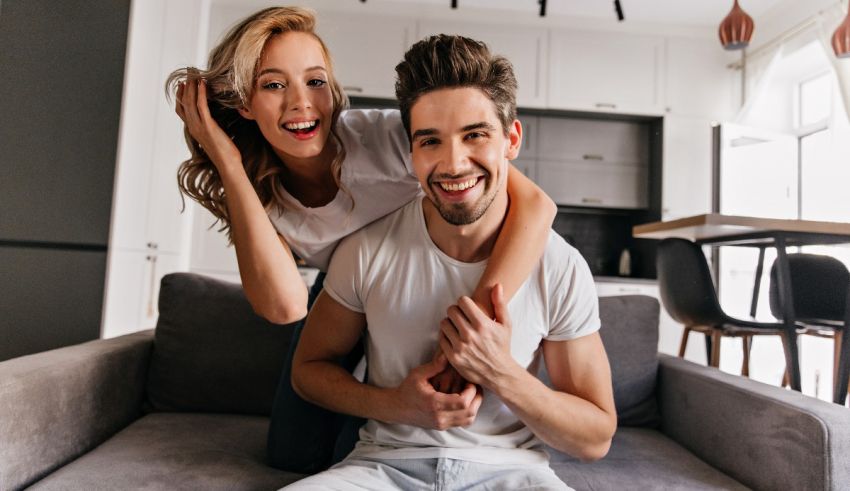 A young man and woman are sitting on a couch in their home.