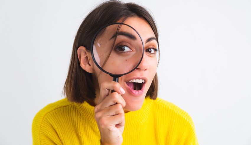 A young woman looking through a magnifying glass.