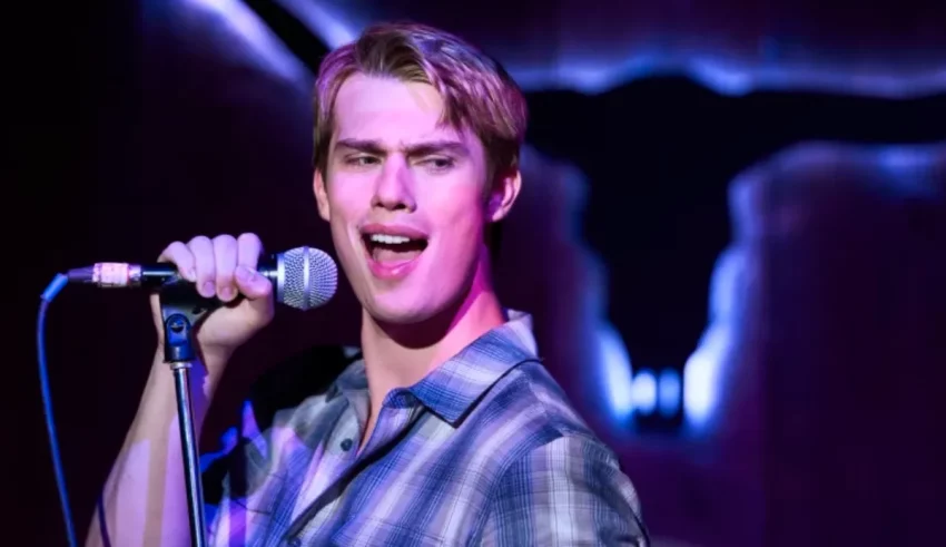 A young man is holding a microphone in front of a cow skull.