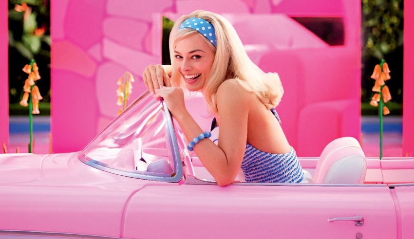 A blonde woman sitting in a pink car.