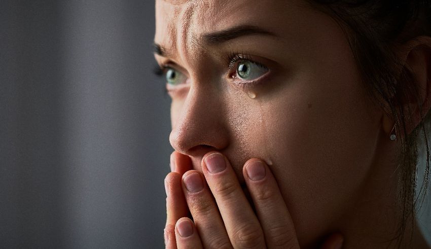 A woman is crying with her hands on her face.