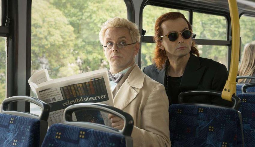 Two men sitting on a bus reading a newspaper.