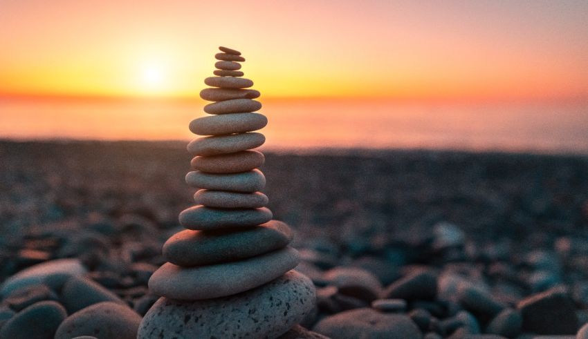 A stack of pebbles on the beach at sunset.