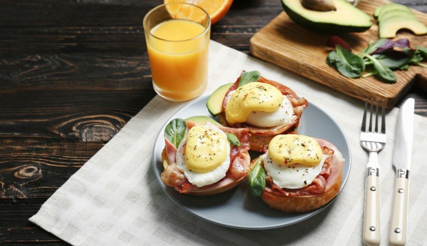 Eggs benedict with bacon and avocado on a plate.