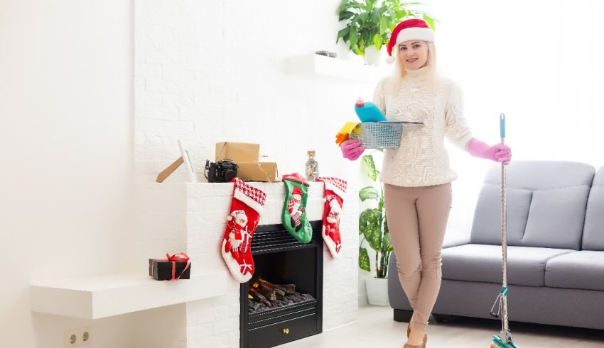 A woman in a santa claus hat is cleaning her living room.
