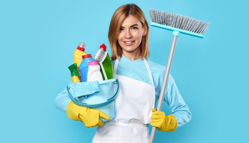 A woman holding a broom and cleaning supplies.