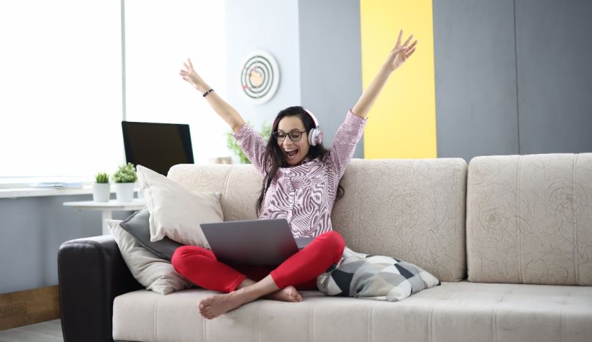 A woman is sitting on a couch and using a laptop.