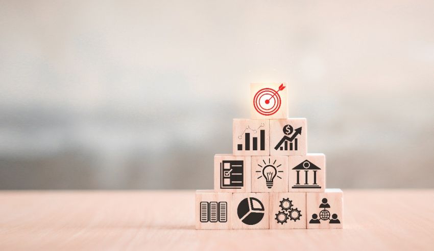 A stack of wooden blocks with business icons on top.