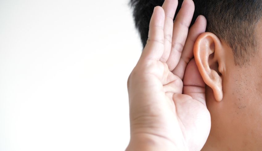 A man is touching his ear with his hand.