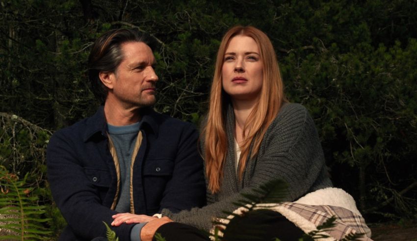 A man and woman sitting next to each other in the woods.