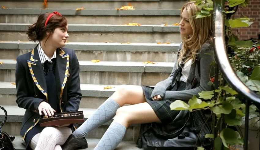 Two girls in school uniforms sitting on steps.