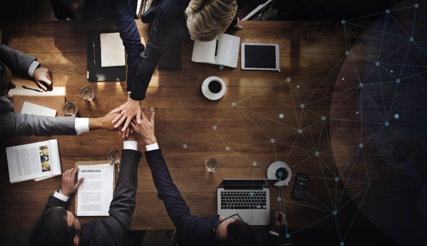 A group of business people holding hands around a table.