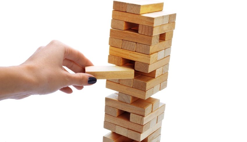 A person's hand reaching up to a wooden tower.