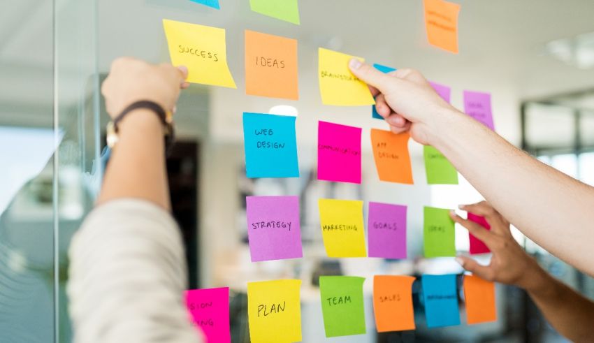 A group of people putting sticky notes on a glass wall.