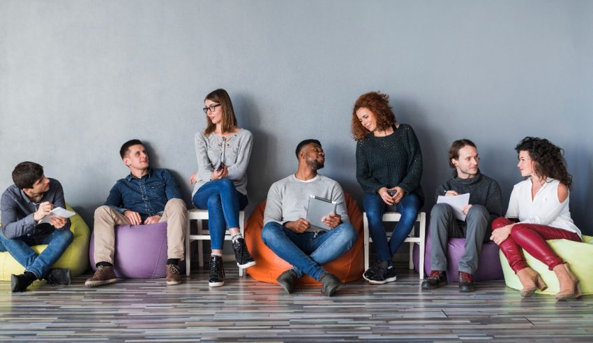 A group of people sitting on bean bags in front of a gray wall.