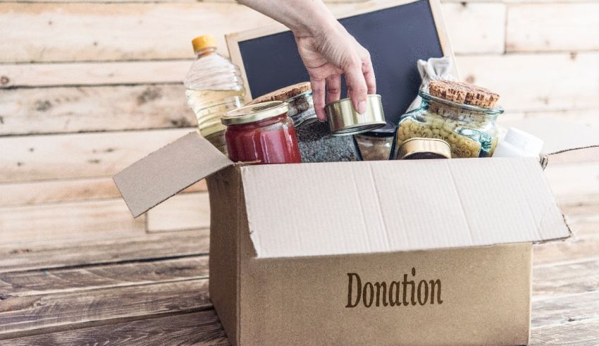 A person opening a cardboard box with food and other items in it.