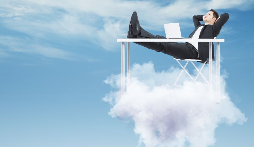 A businessman sitting on a cloud with a laptop.