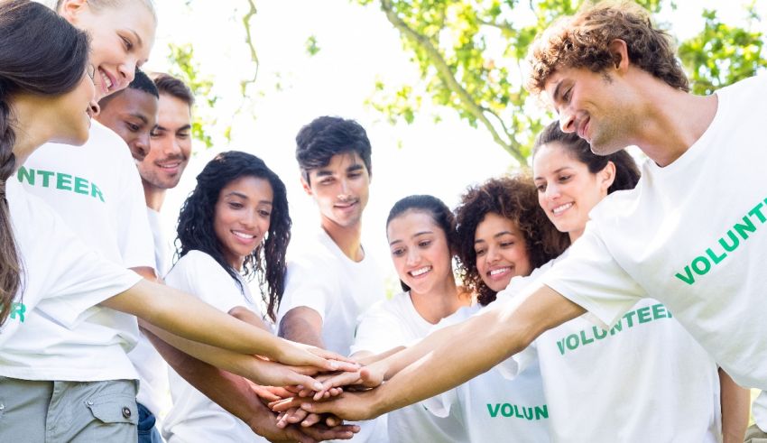 A group of people in white t - shirts holding hands.