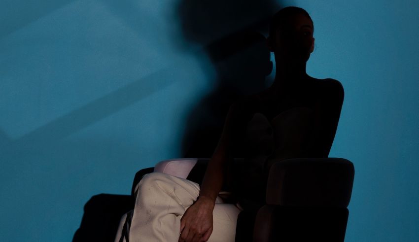 A woman sitting on a chair in front of a blue wall.