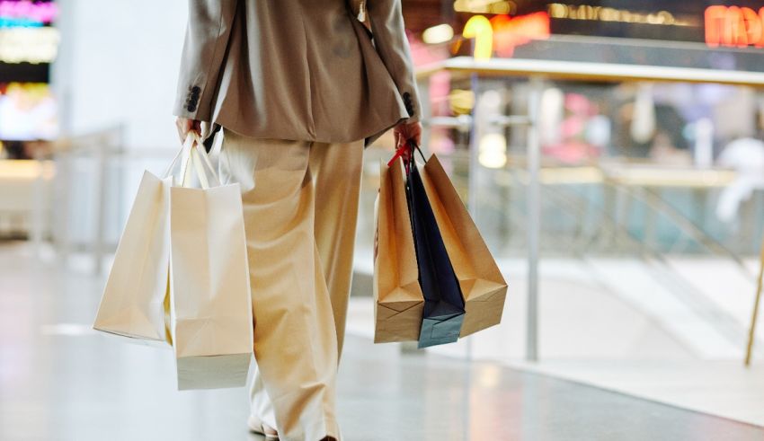 A woman walking down a mall with shopping bags.