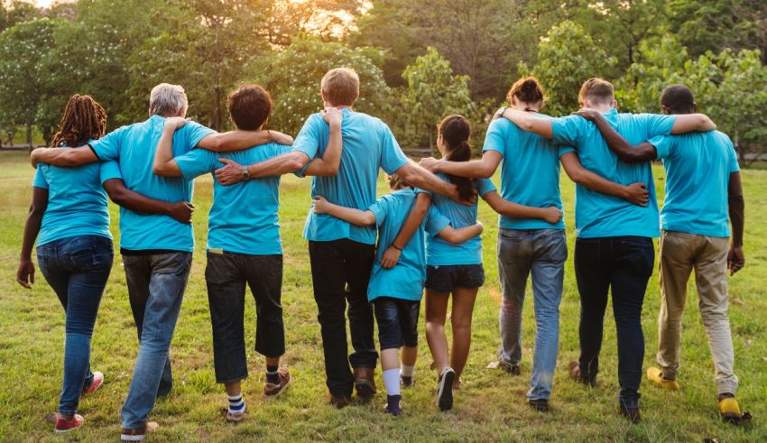 A group of people in blue shirts standing together in a park.