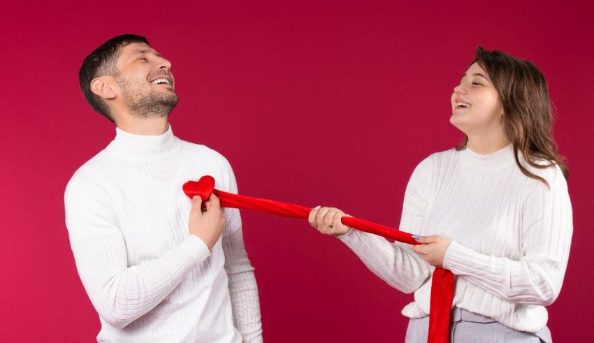 A man and a woman holding a red ribbon on valentine's day.