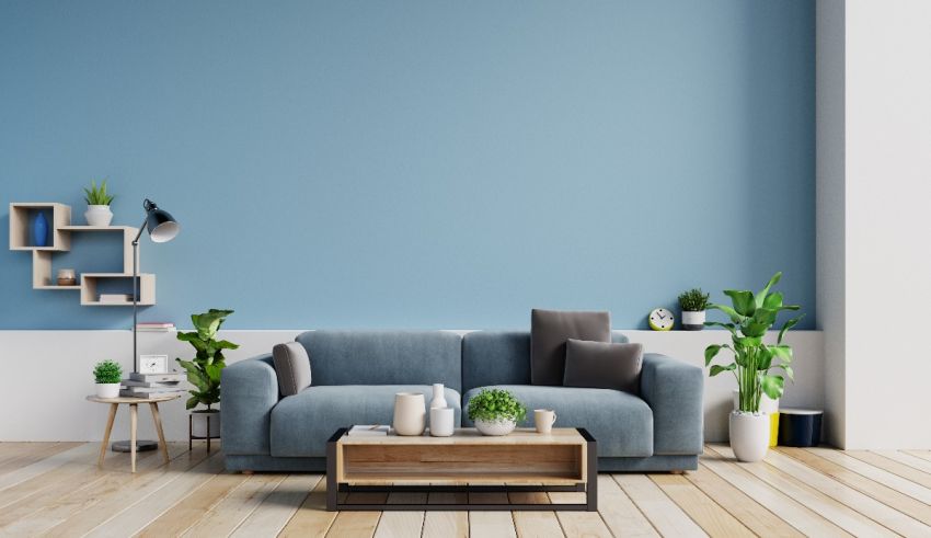A living room with blue walls and a grey couch.