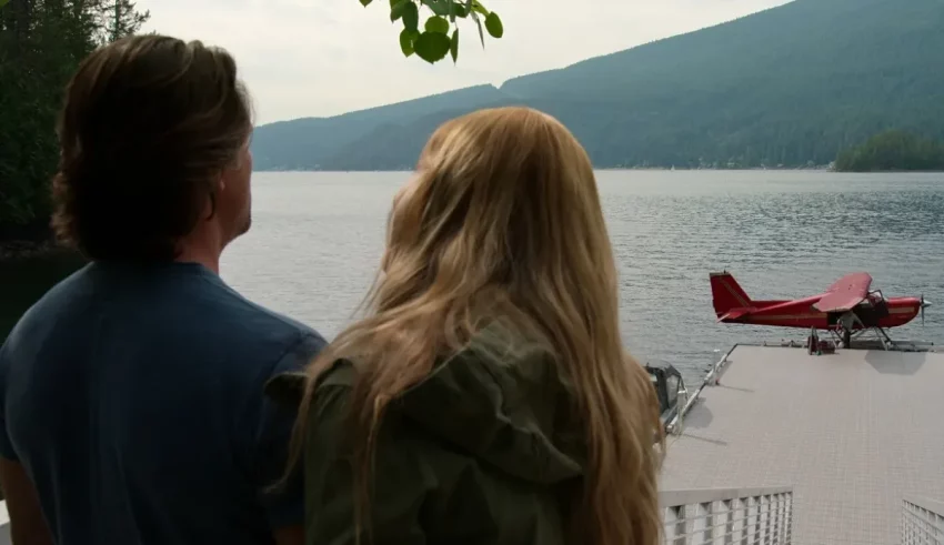A man and woman standing on a dock looking at a plane.