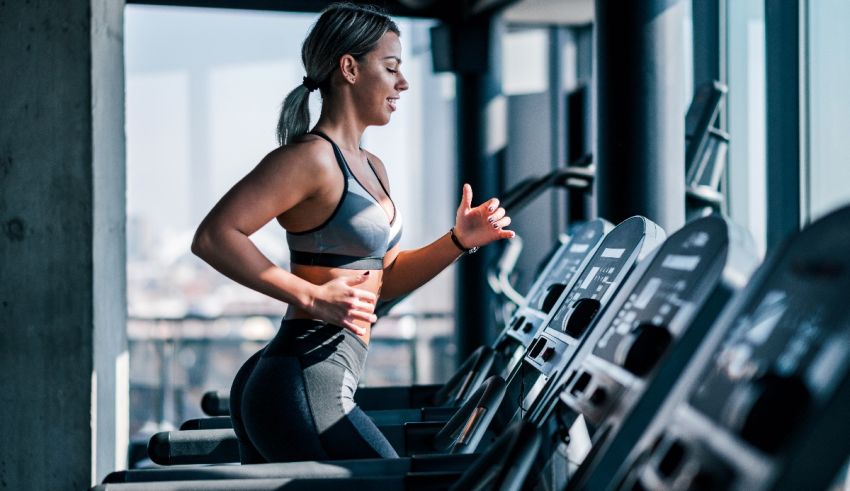 A woman is running on a treadmill in a gym.