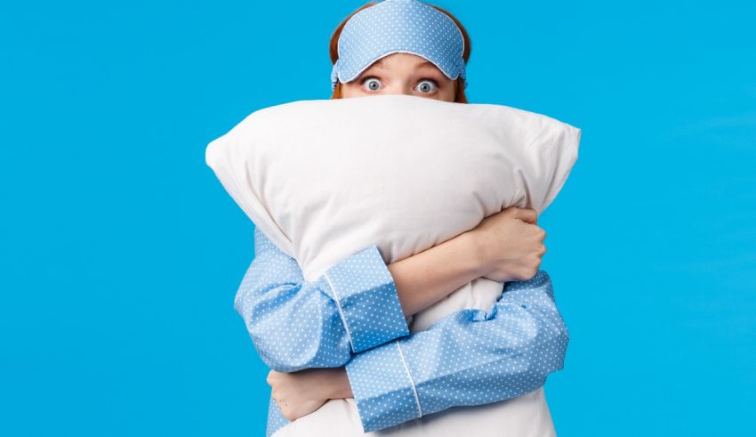 A woman with a pillow covering her face on a blue background.