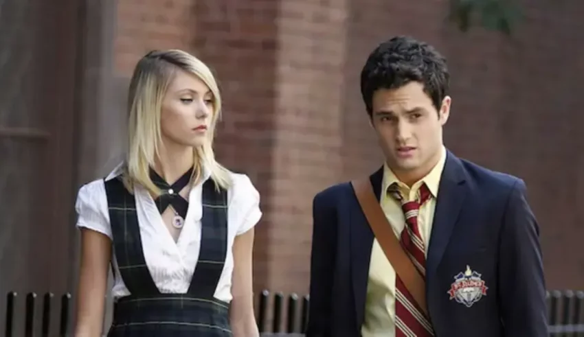 A man and woman dressed in school uniforms walking down the street.