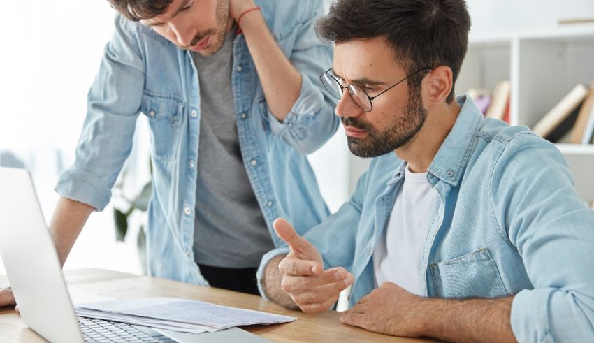 Two men working on a laptop in an office.