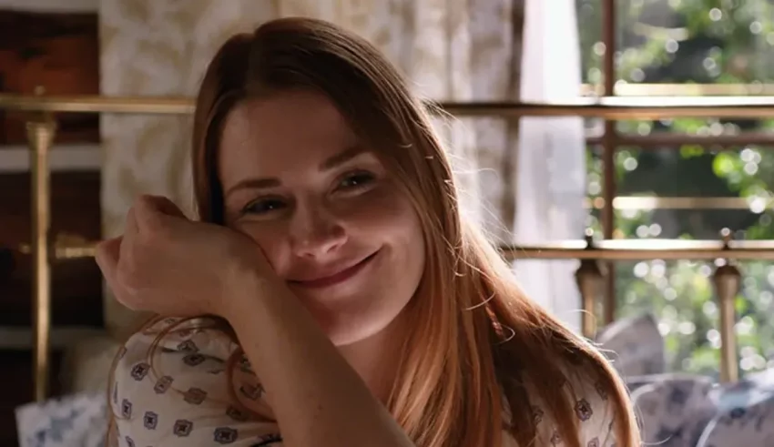 A young woman is sitting on a bed and smiling.