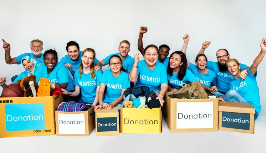 A group of people in blue shirts posing with boxes.