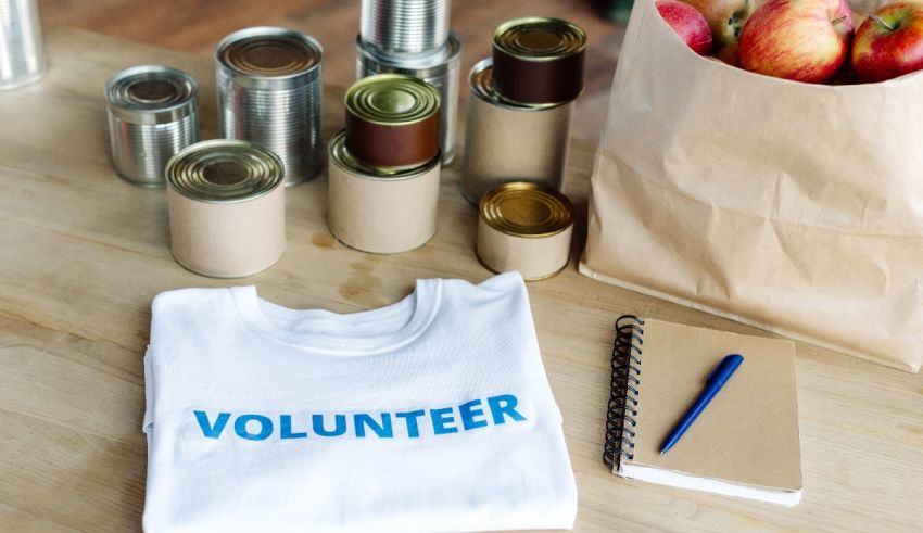 A white t - shirt with the word volunteer next to apples and a notebook.