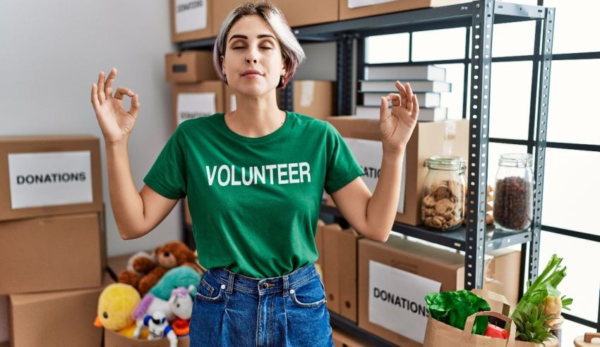 A woman in a green t - shirt is standing in a room full of boxes.