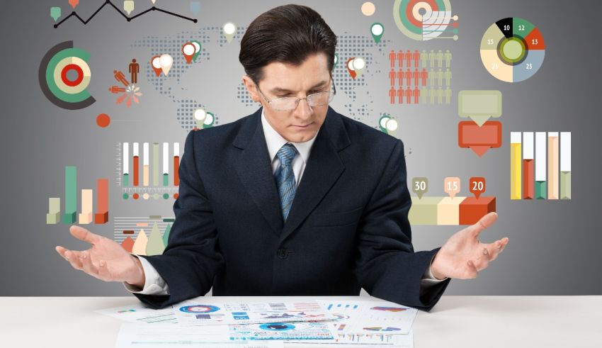 A businessman in a suit sitting at a table with graphs and icons.