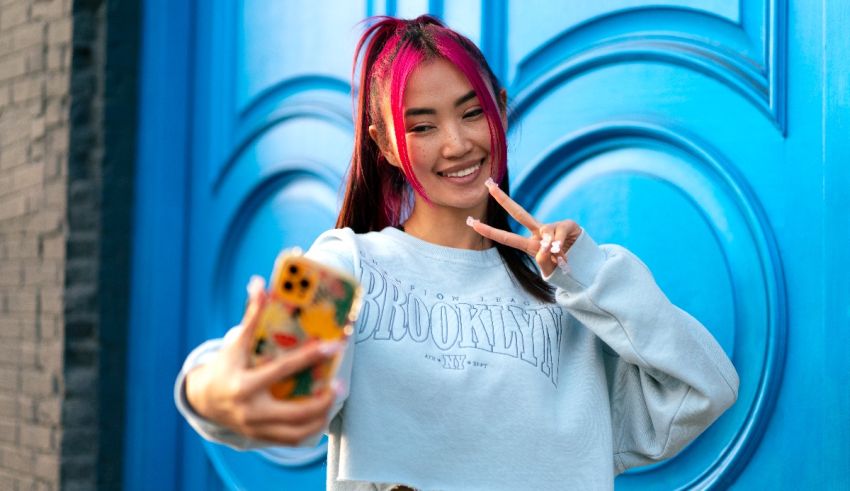 A woman with pink hair taking a selfie with a blue door.