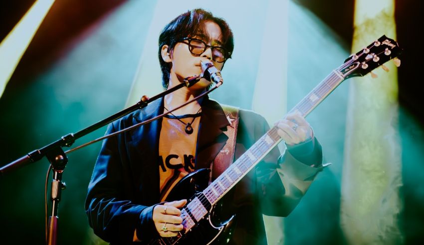 A man holding a guitar in front of a microphone.