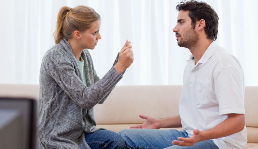 A man and woman sitting on a couch talking to each other.