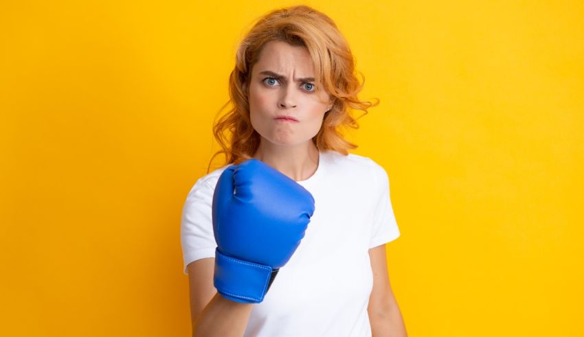 A young woman with blue boxing gloves on a yellow background.