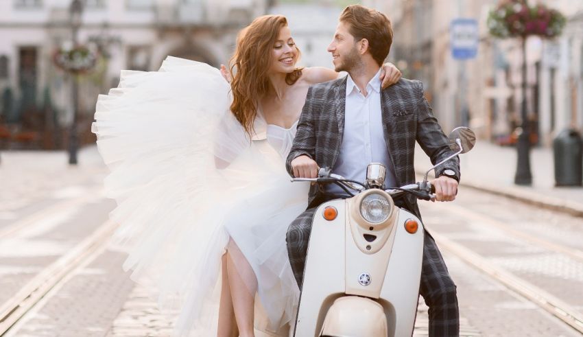 A bride and groom riding a scooter in a city.