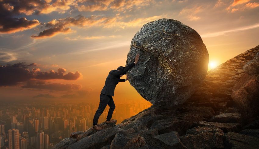 A businessman pushing a large rock up a mountain.