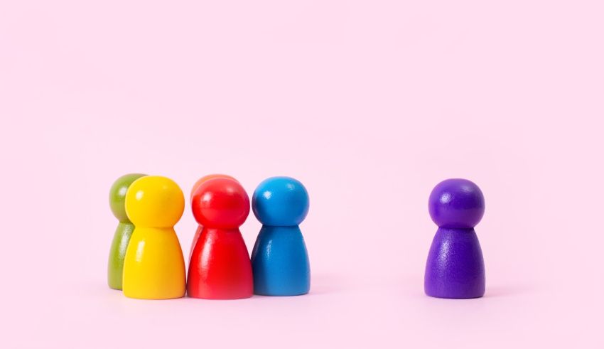 A group of colorful wooden figures standing next to each other on a pink background.