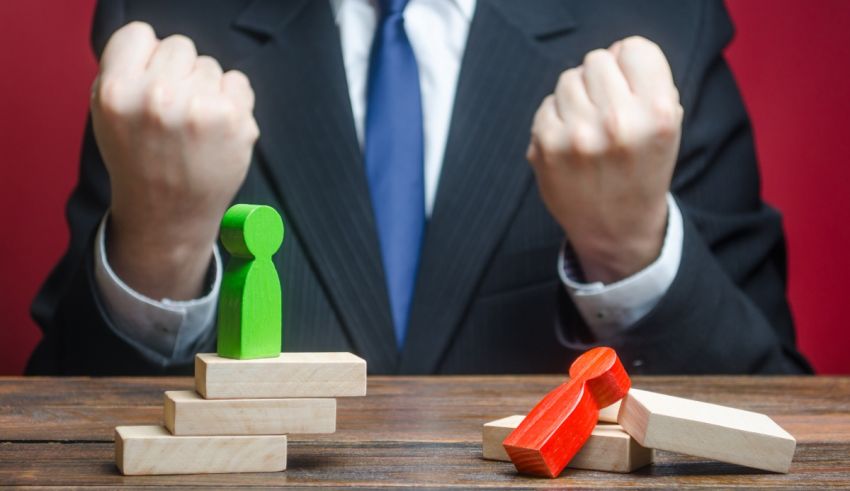 A businessman in a suit is standing on top of wooden blocks with his fists up.