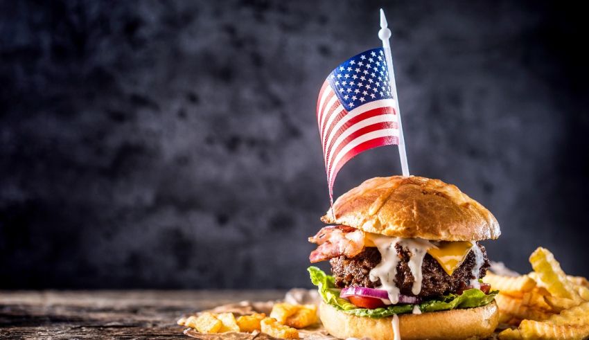 A hamburger with an american flag and french fries.