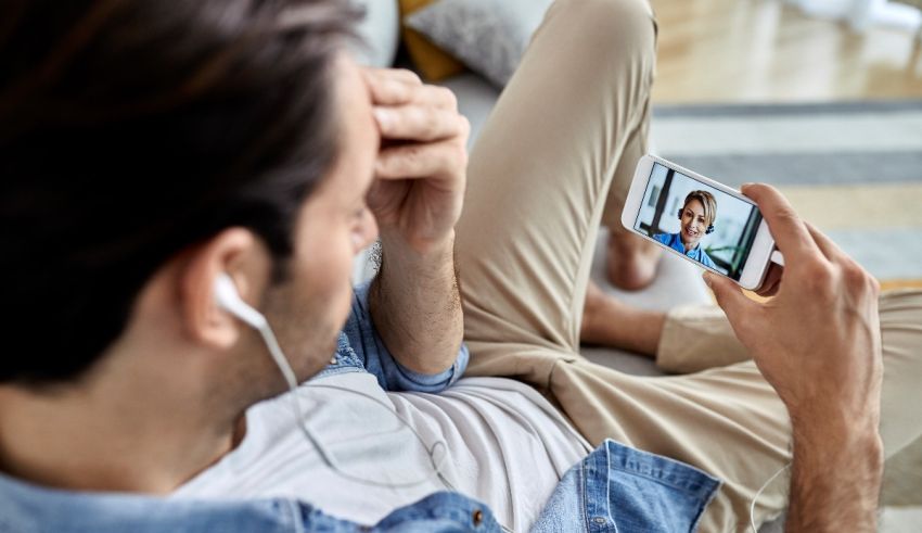 A man is sitting on a couch with his phone in his hand.