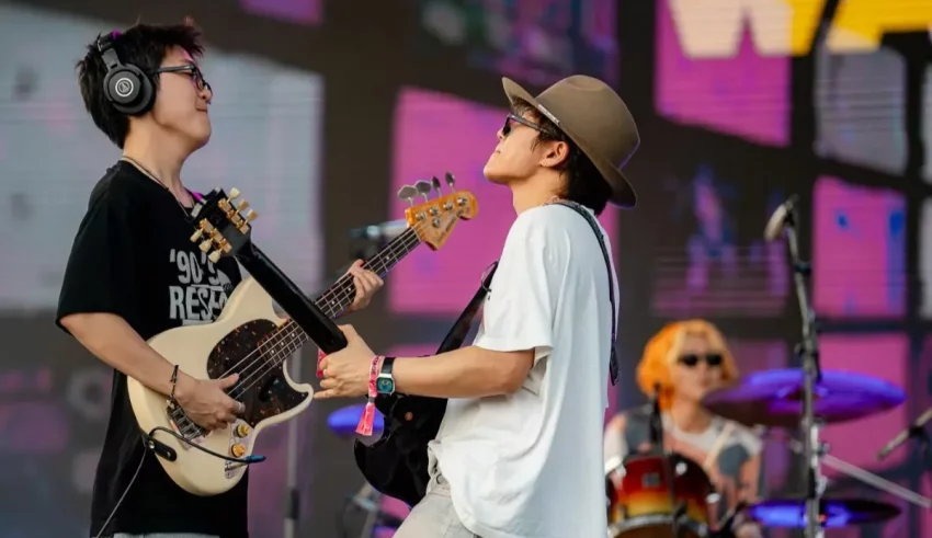 Two men playing guitars on stage at a music festival.