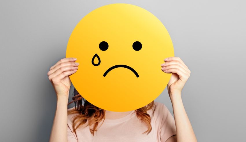 A woman covering her face with a yellow emoticon.