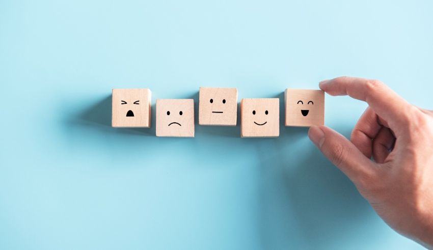 A hand is holding a set of wooden cubes with different emoticons on them.